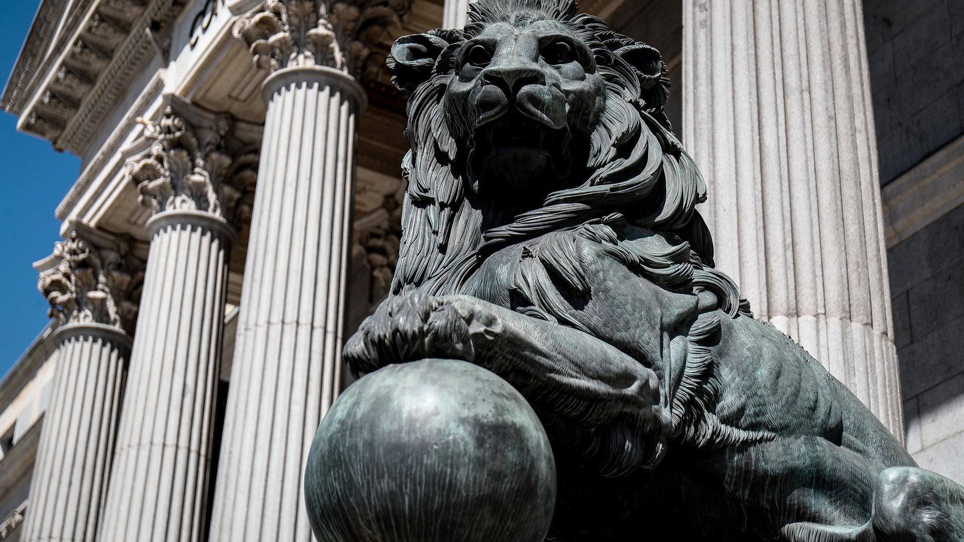 Archivo - Uno de los emblemáticos leones que se encuentran delante de la fachada del Congreso de los Diputados en la Plaza de las Cortes de Madrid.