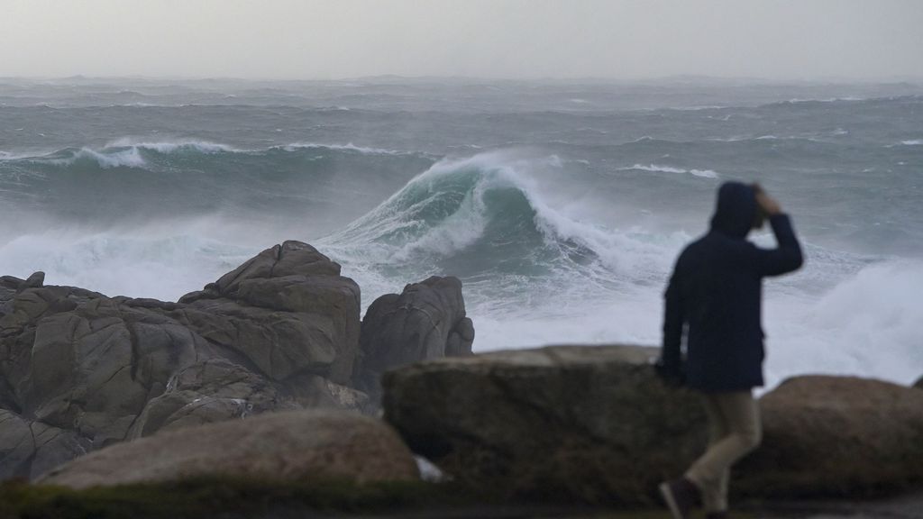 Une personne marche le long de la promenade en regardant la mer agitée à La Corogne