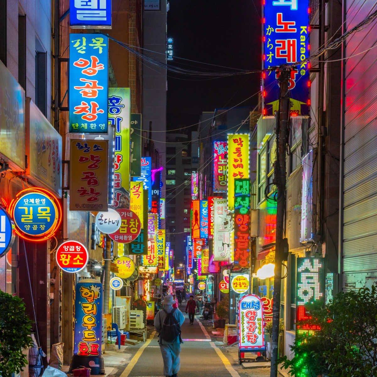 Gens marchant dans une rue éclairée au néon à Busan, Corée du Sud