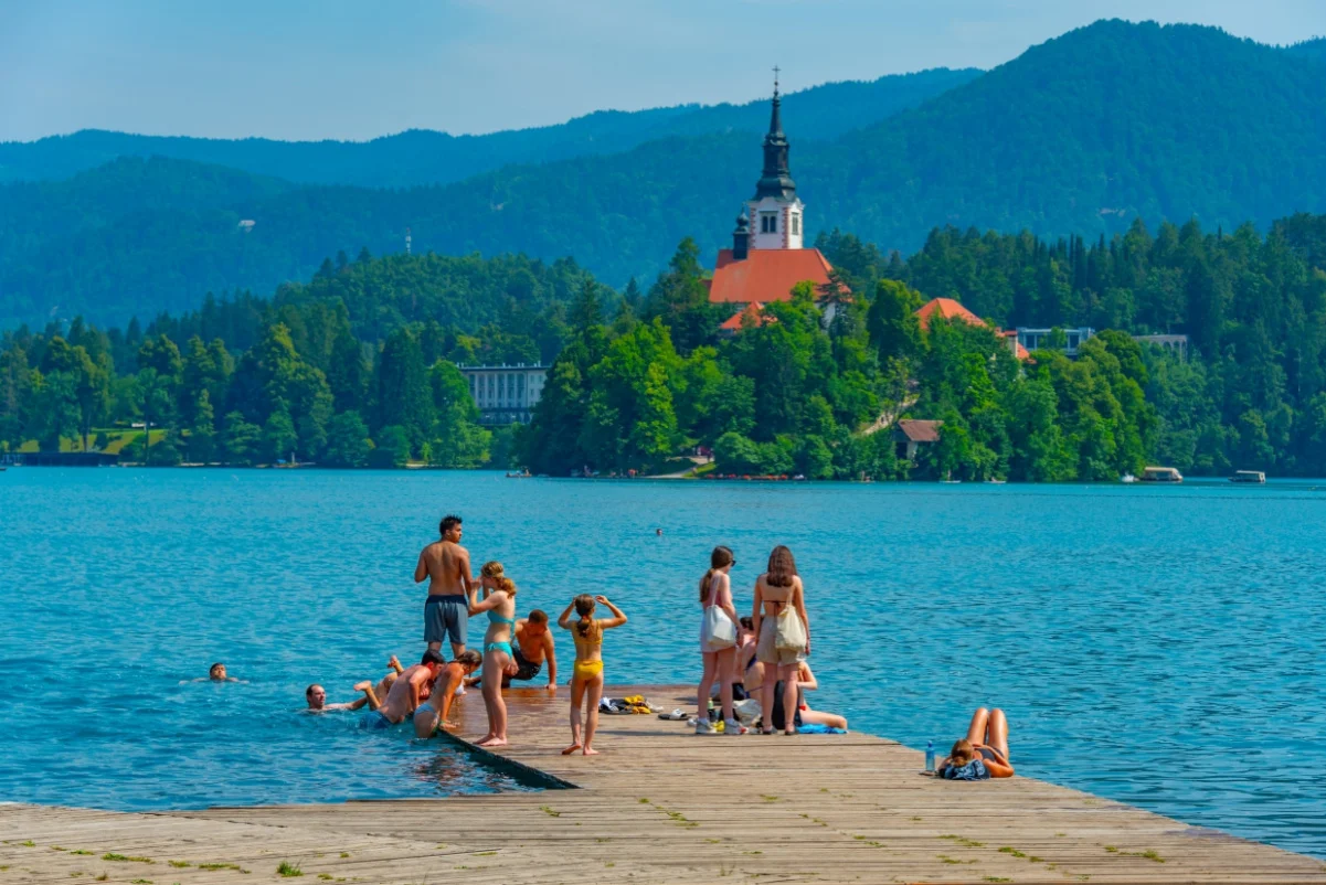 Les gens nagent devant l’église de l’Assomption de Maria au lac de Bled en Slovénie