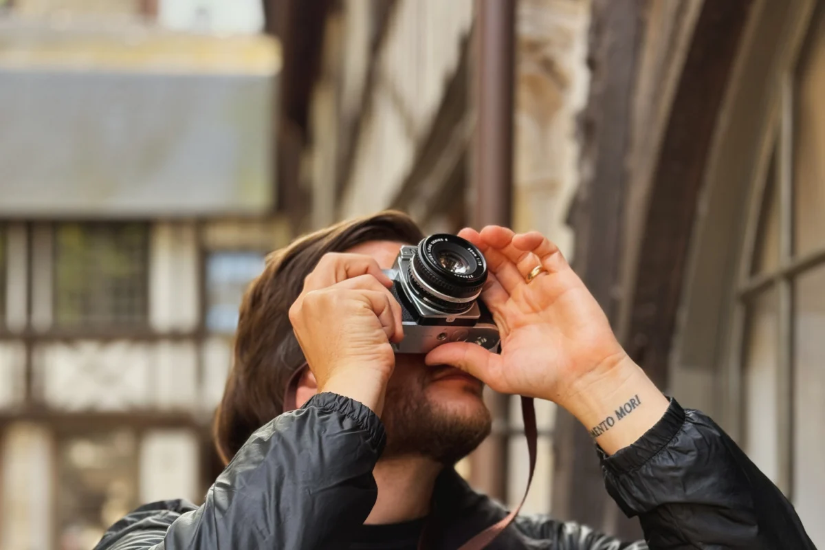 Homme prenant une photo avec un appareil photo argentique du bâtiment à Rouen, France