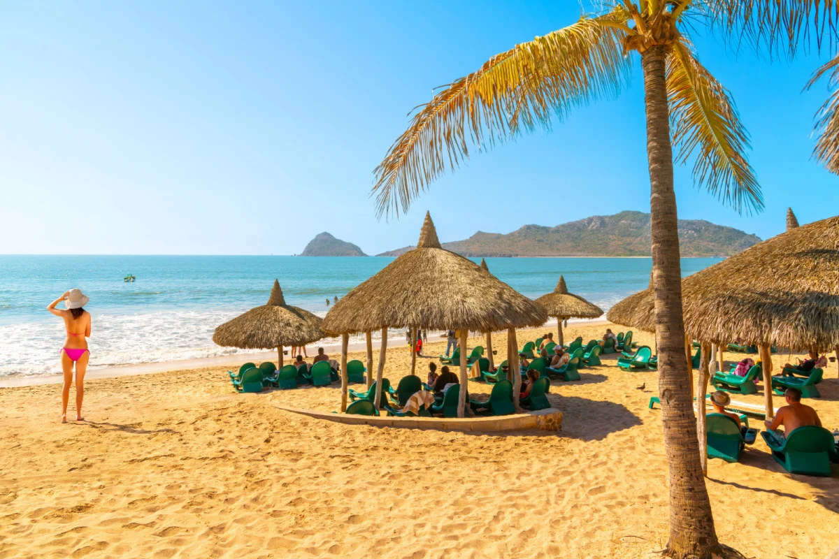 Les touristes profitent d'un club de villégiature privé avec des cabanes en paille le long de la plage de sable Playa Gaviotas, dans la zone dorée de Mazatlan, au Mexique, le long de la Riviera de Sinaloa.