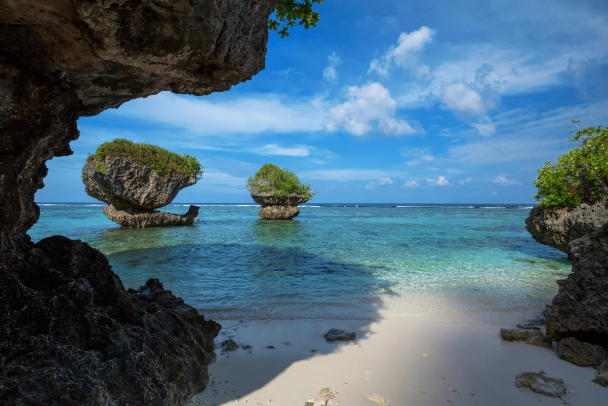 De belles formations rocheuses le long de la plage de sable de Tanguisson Beach sur l'île tropicale de Guam pendant le calme matinal de l'océan par une journée claire et ensoleillée