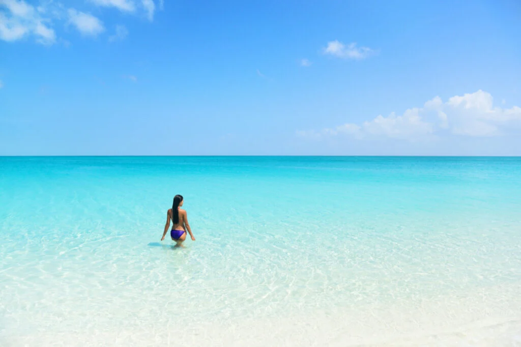 Femme entrant dans l'océan dans l'eau bleue cristalline de South Caicos