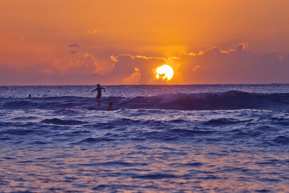 Un jeune surfeur se découpe sur le soleil couchant à Domes Beach. Rincon est une destination de surf populaire auprès des touristes pendant les mois d'hiver.