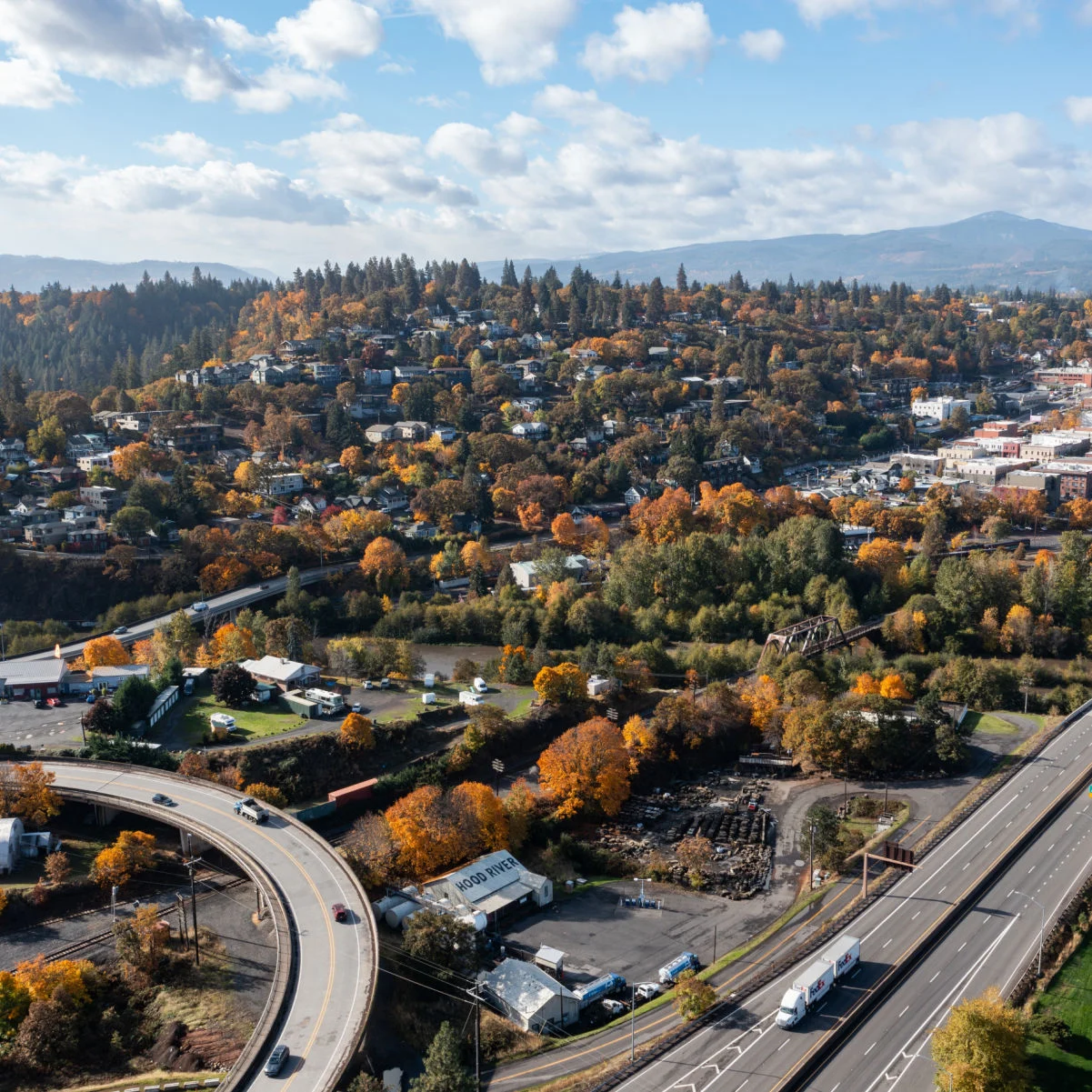 Photo aérienne d'un drone de Hood River, Oregon, montrant le paysage urbain, le trafic sur l'autoroute I-84, la station-service Chevron, le camion Fedex, Best Western, les arbres colorés en automne
