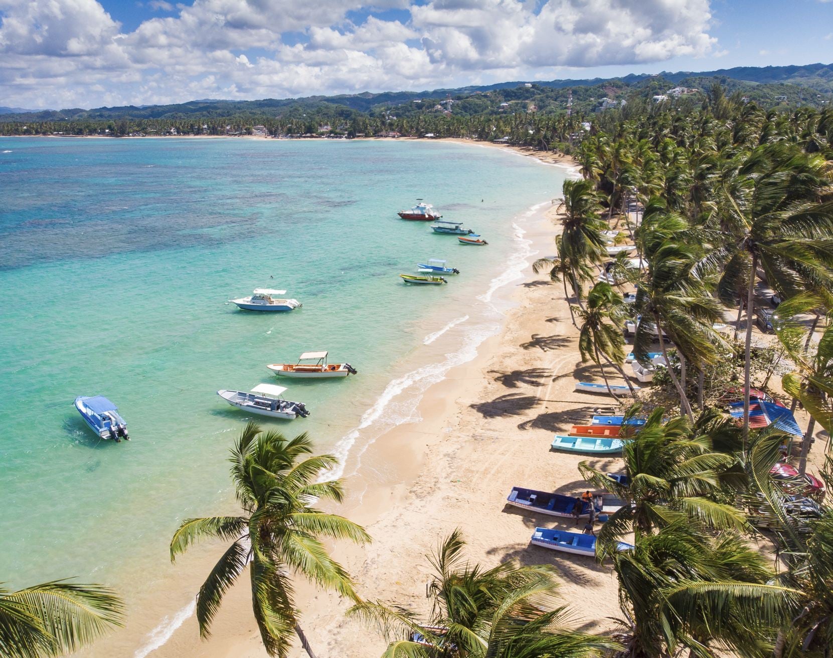Vue panoramique par drone aérien de la plage paradisiaque avec rivage sablonneux, taches de corail, palmiers, bateaux colorés et eau bleue de l'océan Atlantique, Las Terrenas, Samana, République Dominicaine