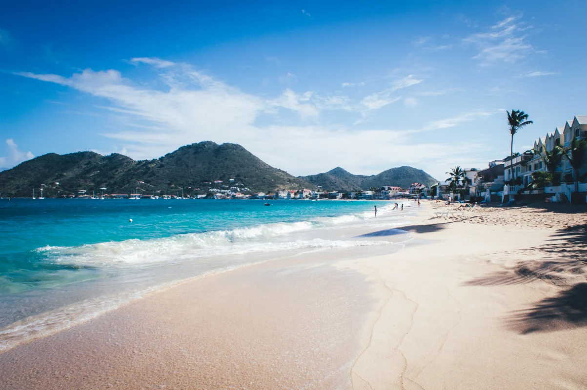 Grand-Case - Saint-Martin - Paysage de plage avec mer bleue transparente et montagne en arrière-plan.