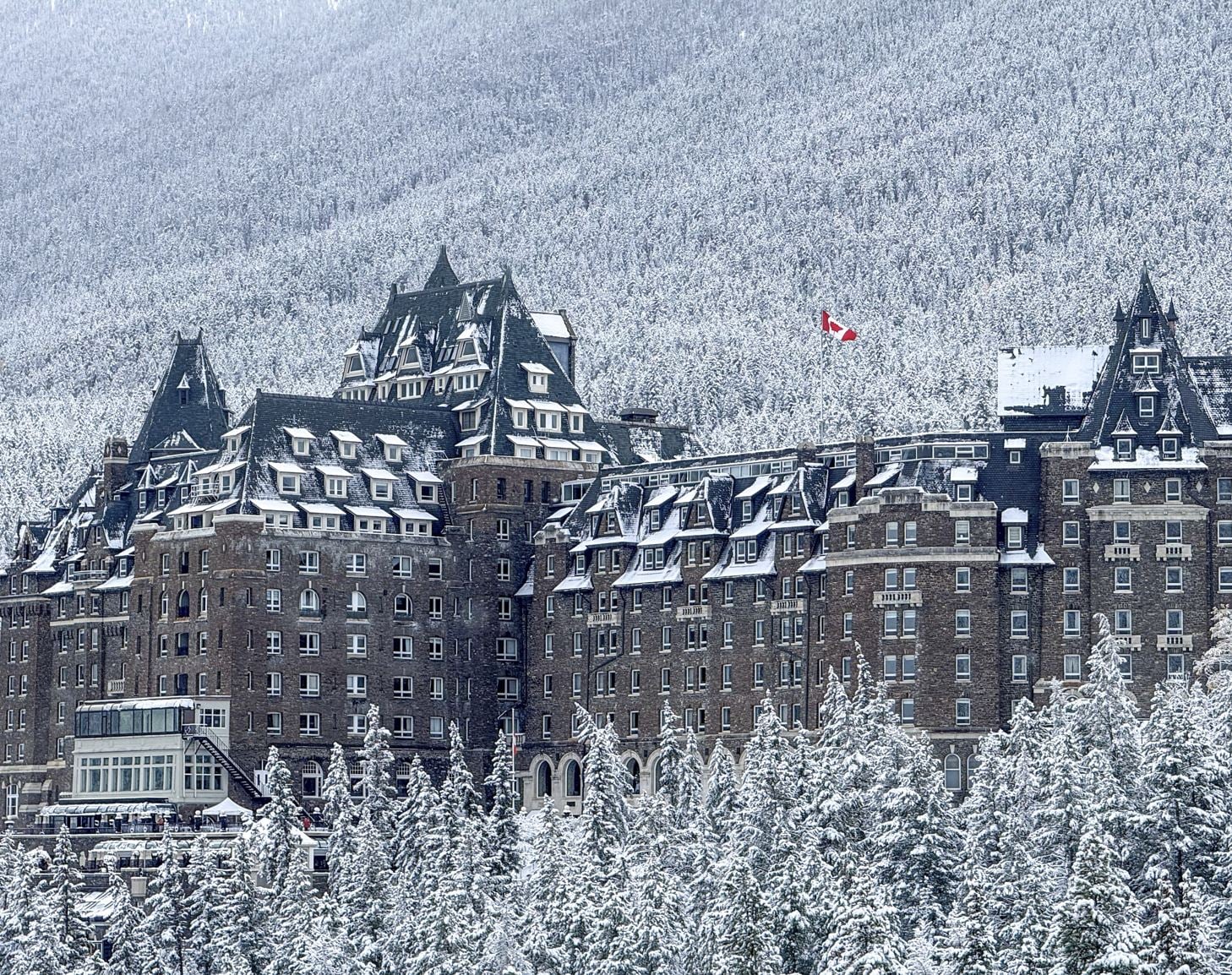 hôtel-château en pierre avec ses toits verts emblématiques recouverts de neige fraîche,