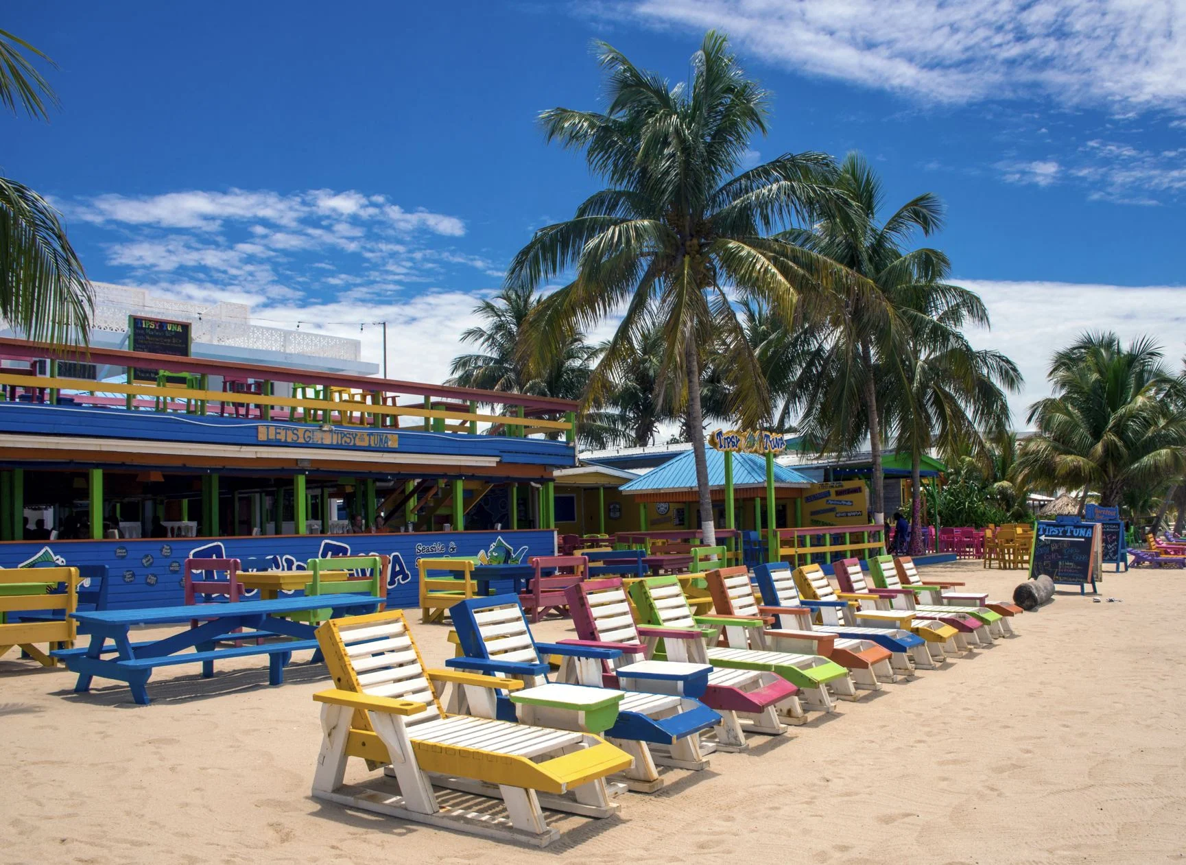   Chaises longues en bois colorées à l'extérieur du bar Tipsy Tuna en bord de mer sur la plage de Placencia,