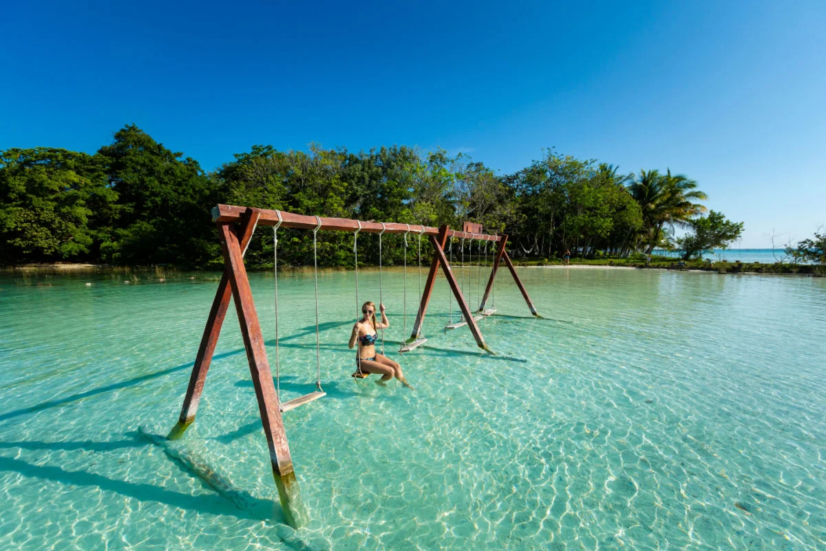 Belle touriste féminine se relaxant sur une balançoire à Laguna Bacalar au Mexique pendant une excursion en kayak.