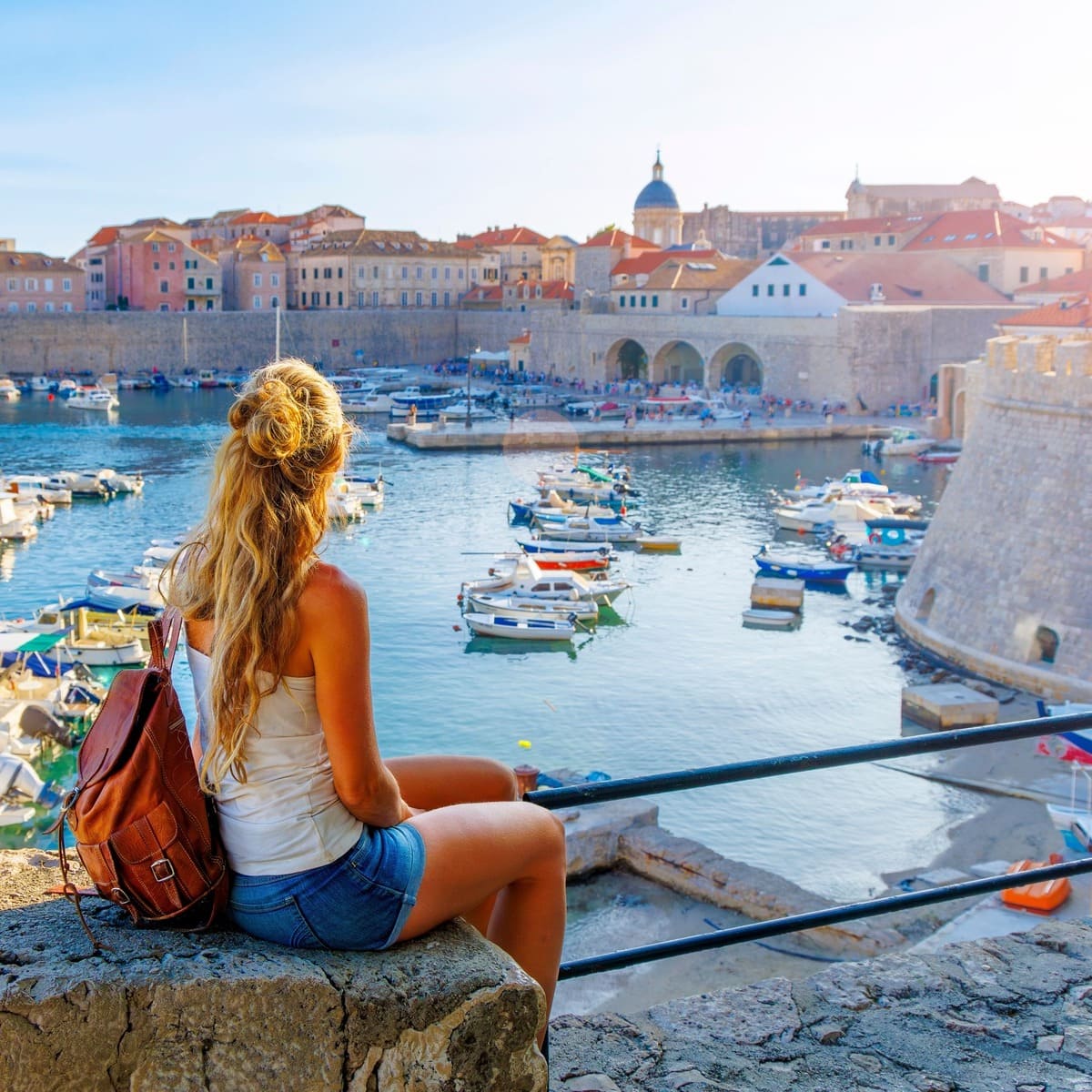 Une touriste assise sur les remparts de Dubrovnik admirant une vue sur la vieille ville, Croatie